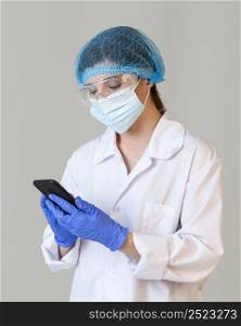 front view female scientist with safety glasses medical mask holding smartphone