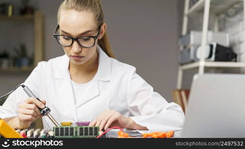 front view female technician with electronics board soldering iron