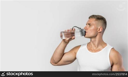 front view fit man drinking from water bottle