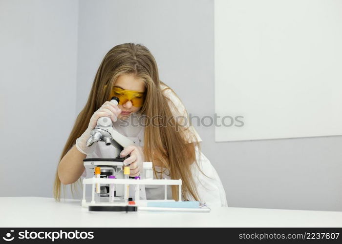 front view girl scientist with safety glasses microscope