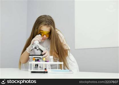 front view girl scientist with safety glasses microscope