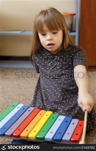front view girl with down syndrome playing with xylophone