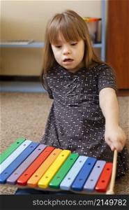 front view girl with down syndrome playing with xylophone