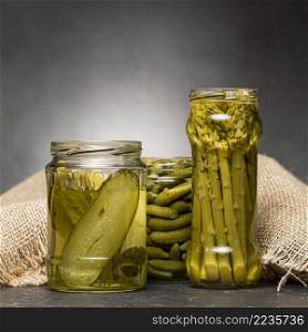front view glass jars with pickled asparagus cucumbers