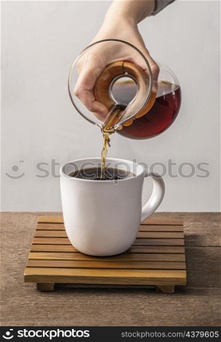 front view hand pouring coffee into mug