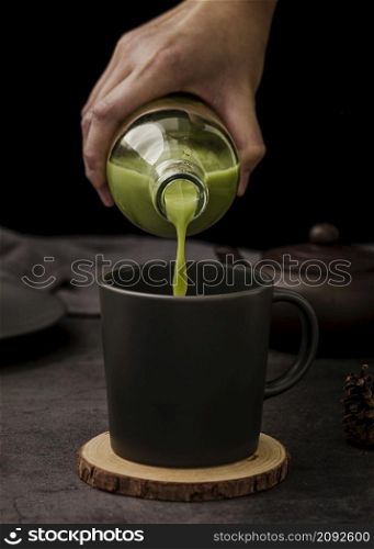 front view hand pouring matcha tea cup