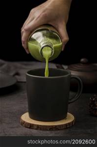 front view hand pouring matcha tea cup