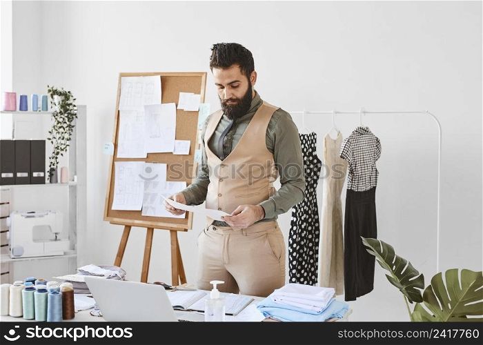 front view handsome male fashion designer working atelier with papers