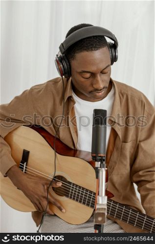 front view handsome male musician home playing guitar