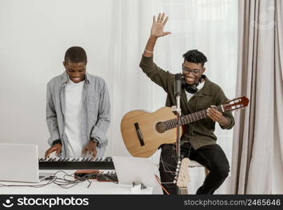 front view handsome male musicians home playing electric keyboard guitar