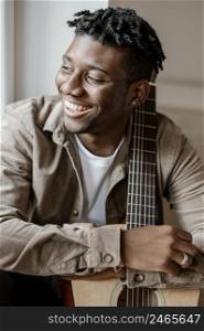 front view handsome smiley male musician home posing with guitar