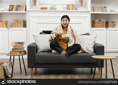 front view happy woman eating popcorn sitting couch