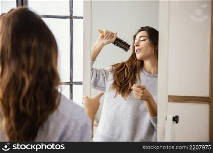 front view happy woman singing into hairbrush home