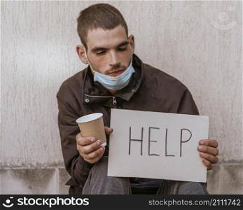 front view homeless man holding cup help sign