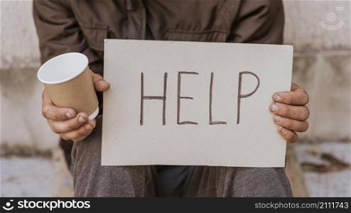 front view homeless man holding help sign cup