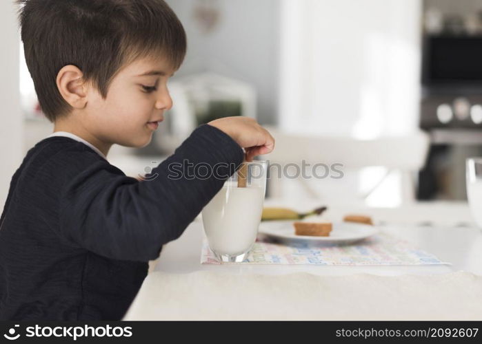 front view kid dipping biscuit milk