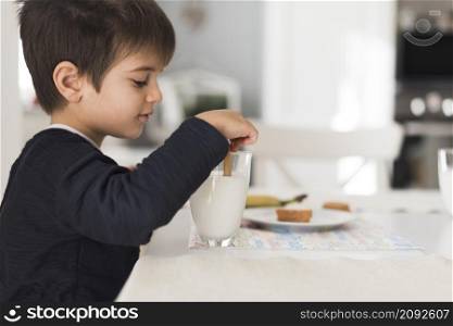 front view kid dipping biscuit milk