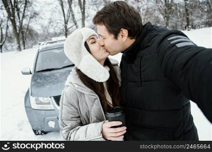 front view kissing couple taking selfie while road trip