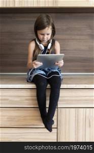front view little girl using tablet with headphones