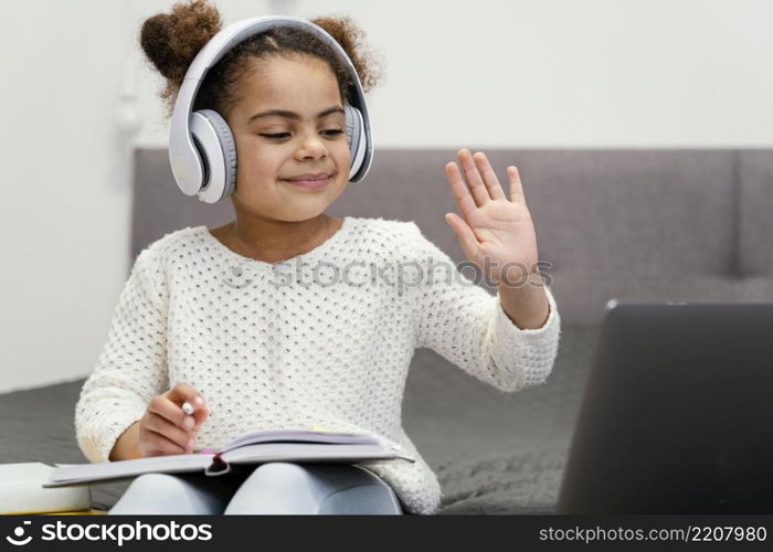 front view little girl waving using laptop online school