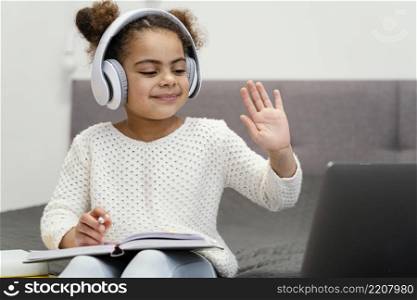 front view little girl waving using laptop online school