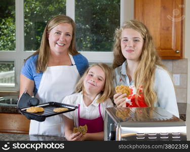 Front view, looking forward, of mother and her daughters eating freshly baked cookies