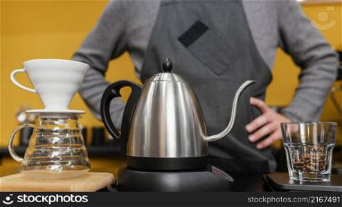 front view male barista with apron preparing coffee with kettle filter