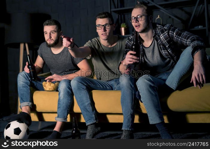 front view male friends watching sports tv together while having snacks beer