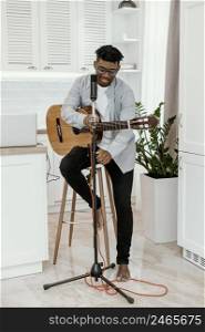 front view male musician home playing guitar with microphone
