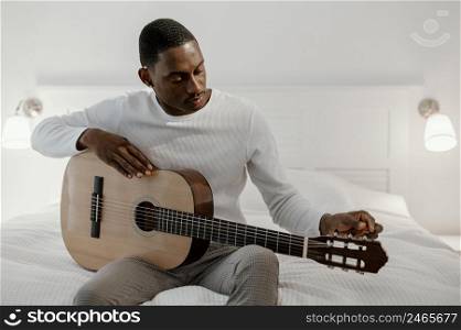 front view male musician playing guitar bed