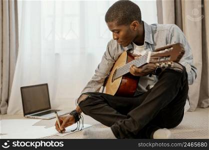 front view male musician writing music with guitar bed laptop