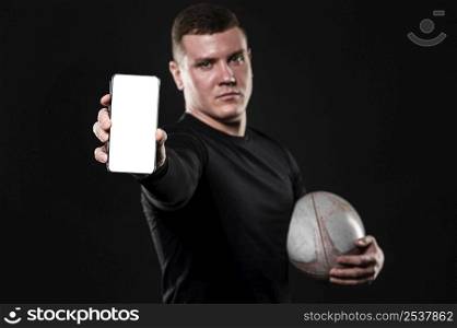 front view male rugby player holding ball smartphone