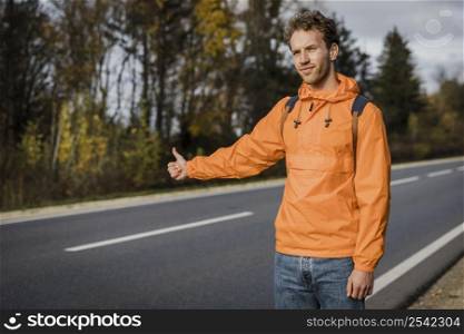 front view man hitchhiking while road trip