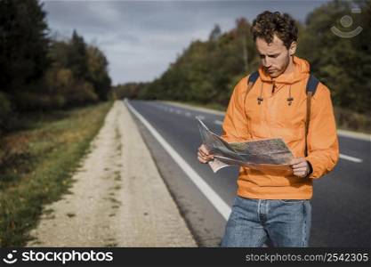 front view man holding map sitting along road
