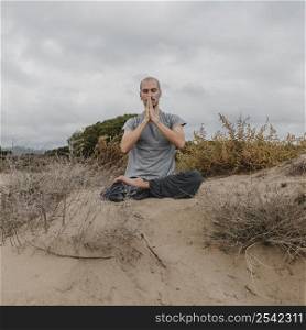 front view man outside relaxing while doing yoga