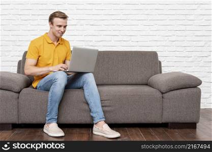 front view man sitting while checking laptop