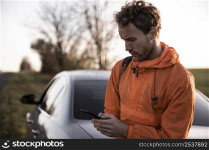 front view man using smartphone outdoors while road trip