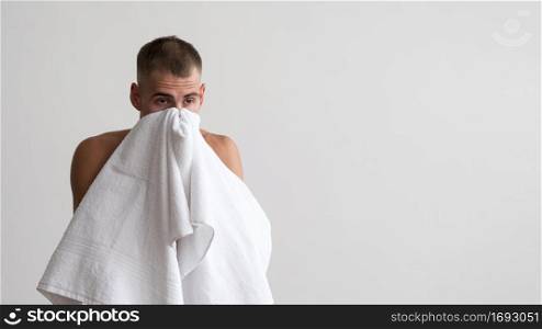 front view man wiping his face with towel after washing