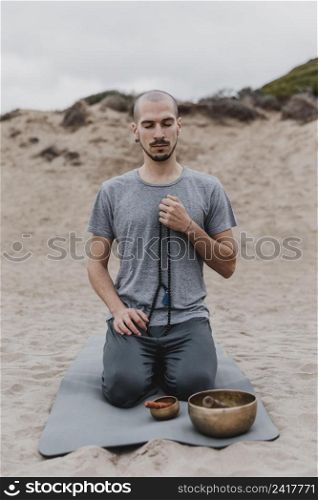 front view man with singing bowl rosary outdoors