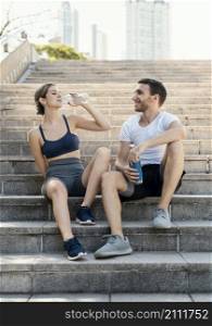 front view man woman drinking water outdoors while exercising