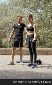 front view man woman outdoors together exercising with dumbbells