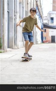 Front view of a cheerful skater boy riding on the street in a sunny day