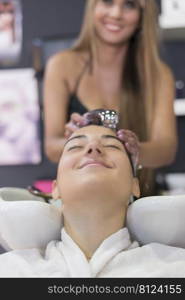 Front view of a hairdresser washing hair of a beautiful young lady in hair salon.