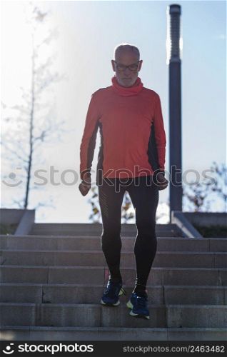 Front view of a senior caucasian athlete male training running up and down the stairs outdoors in a park in a sunny day