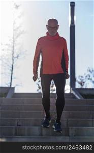 Front view of a senior caucasian athlete male training running up and down the stairs outdoors in a park in a sunny day