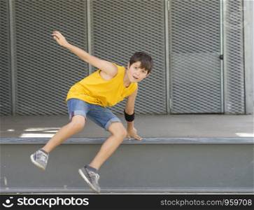 Front view of a smiling boy jumping over a metallic fence while looking camera on a bright day