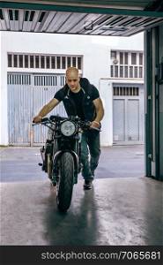 Front view of biker taking custom motorbike to the garage. Biker taking motorbike to the garage