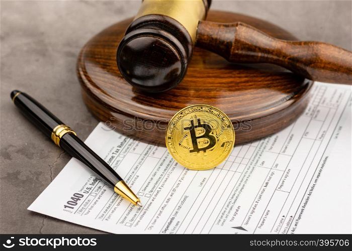Front view of Bitcoin cryptocurrency in ront of gavel with pen.Tax paying concept.