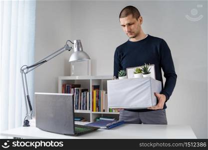 Front view of caucasian man holding box with his personal belongings at the office - Male adult being fired from work taking his stuff after losing job - recession economic financial crisis concept