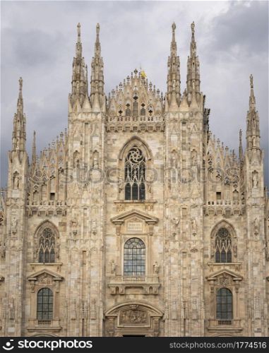 "Front view of Duomo with the golden statue name "Madonnina" on the top of the main spire,overcast sky."